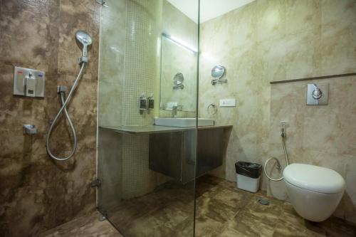 a bathroom with a shower and a toilet and a sink at Vesta Grand Central Udaipur in Udaipur
