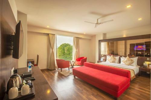 a hotel room with a bed and a red couch at Vesta Grand Central Udaipur in Udaipur