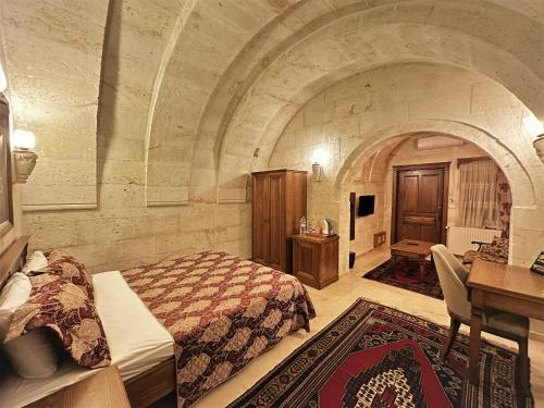 a bedroom with a bed and a desk in a room at Stone House Cave Hotel in Goreme