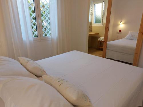 un letto bianco in una stanza con due finestre di Villa Juanes. Encanto, privacidad y relax. a Cala'n Bosch