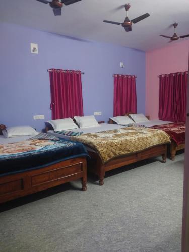 two beds in a room with red curtains at SURYA VILLA GUEST HOUSE in Tajpur