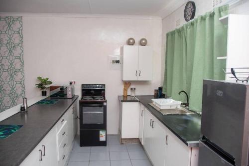 eine Küche mit weißen Schränken und einem schwarzen Kühlschrank in der Unterkunft Laha Apartment 3 in Maun