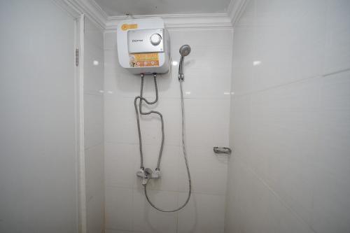eine Dusche in einem weiß gefliesten Bad mit einer Kaffeemaschine in der Unterkunft Perfect Stay Apartement The Suites Metro Bandung By Sultan Property in Bandung