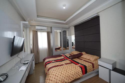 a bedroom with a bed and a desk and a television at Perfect Stay Apartement The Suites Metro Bandung By Sultan Property in Bandung