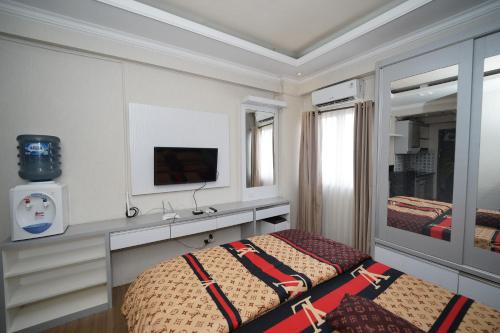 ein Schlafzimmer mit einem Bett und einem TV an der Wand in der Unterkunft Perfect Stay Apartement The Suites Metro Bandung By Sultan Property in Bandung