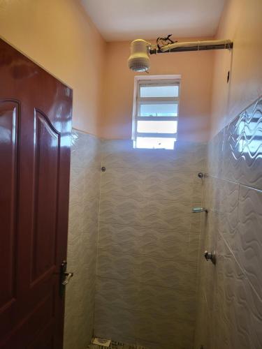 uma casa de banho com um chuveiro e uma porta de vidro em G&G Homes Pipeline Nakuru em Nakuru