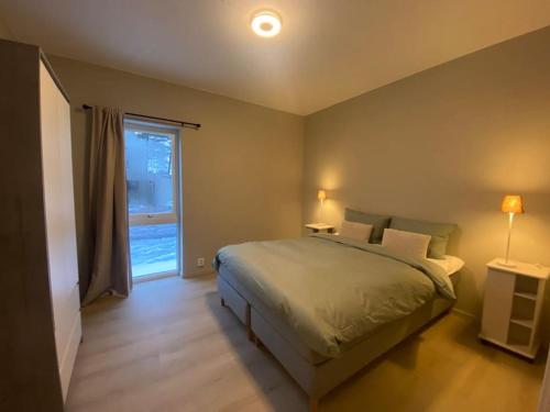 Un dormitorio con una cama grande y una ventana en Helt ny leilighet i rolig område, en Sandefjord