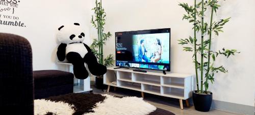 a room with a panda bear sitting in front of a television at Logan's Transient Home - U2 Apartment with Balcony in Baguio
