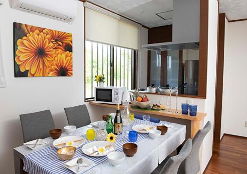 a dining room with a table and a kitchen at Miyakojima White House Annex in Miyako-jima