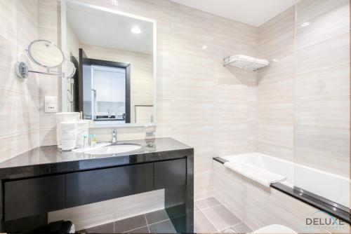 a bathroom with a sink and a tub and a mirror at Cozy Studio in Damac Celestia A Dubai South by Deluxe Holiday Homes in Dubai