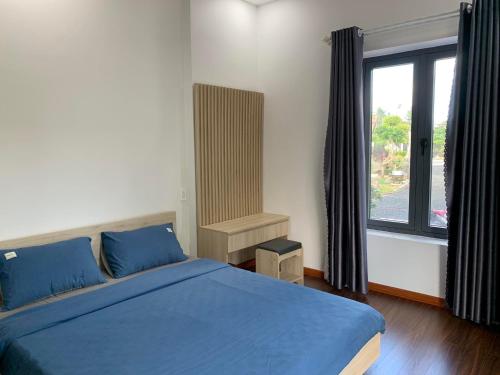 a bedroom with a blue bed and a large window at SATURDAY Homestay Tuy Hòa - Phú Yên in Tuy An