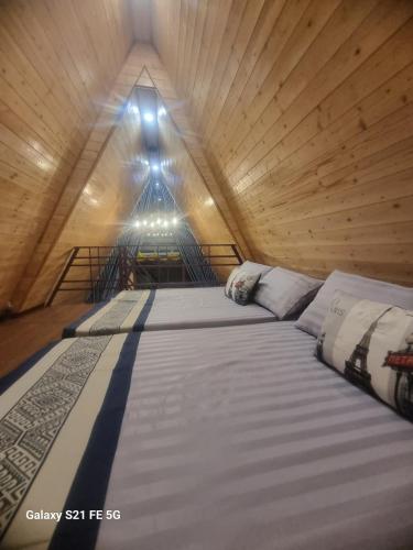 a large bed in a wooden room with a window at Hồ Mây Homestay in Bảo Lâm