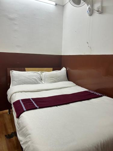 a bedroom with a large bed with white and burgundy sheets at Hotel Sumeru in Kathmandu