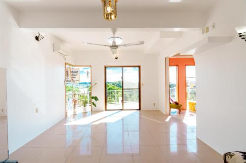 a living room with white walls and a ceiling fan at Tropical Soul Okinawa in Teruya