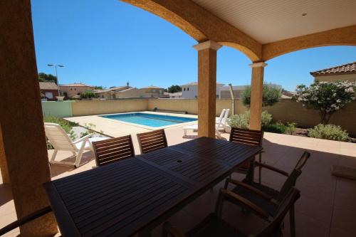 un patio avec une table et des chaises et une piscine dans l'établissement Superbe villa climatisée clôturée, WIFI, 3 km de la mer, 4 belles chambres, piscine privée sur les hauteurs du village LXTOU21, à Portiragnes