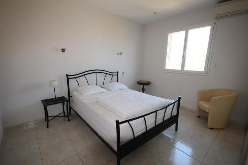 une chambre avec un lit, une chaise et une fenêtre dans l'établissement Superbe villa climatisée clôturée, WIFI, 3 km de la mer, 4 belles chambres, piscine privée sur les hauteurs du village LXTOU21, à Portiragnes