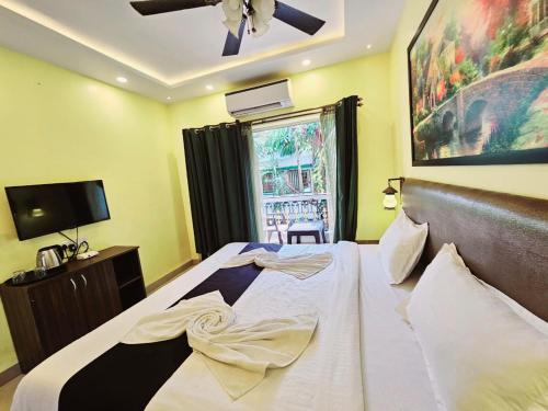 Hotel Adam's Baga Beach Resort Goa - 2 minutes walk from Baga Beach في باغا: غرفة نوم بسرير كبير مع مروحة سقف