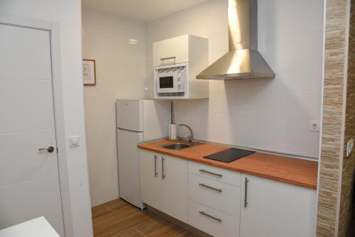Una cocina blanca con fregadero y microondas. en LA VILLA DE ORGAZ II, en Toledo