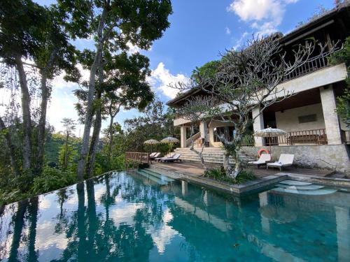 a villa with a swimming pool in front of a house at Natura Villa Ubud Bali in Ubud