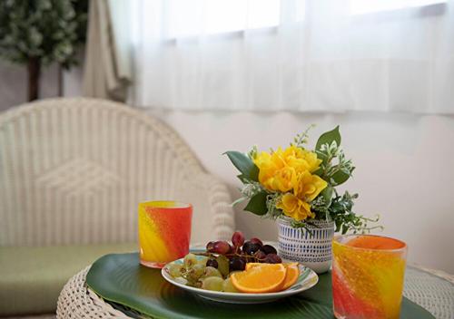 a table with a plate of fruit and a vase of flowers at Miyakojima White House Annex in Miyako-jima