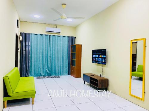 sala de estar con TV y silla verde en ANJU HOMESTAY BEAUFORT en Beaufort