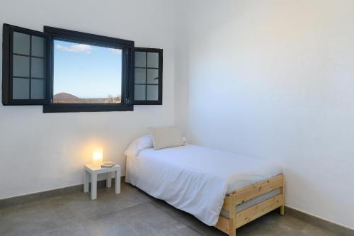 Habitación blanca con cama y ventana en Casa SAS La Hoya, en Yaiza