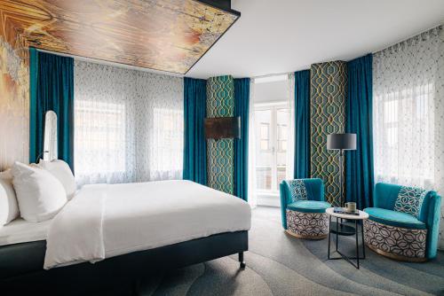 a bedroom with a bed and two blue chairs at Eden Hotel Amsterdam in Amsterdam