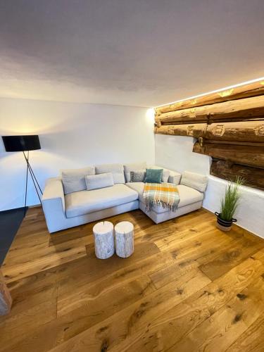 a living room with a white couch and wooden floors at Ferienwohnungen JHS in Seewis im Prättigau
