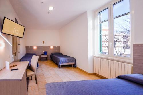 a room with two beds and a desk and a window at Casa San Giuseppe in Rome