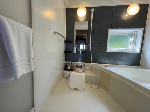 a bathroom with a tub and a toilet and a sink at Chalet Fuyuri in Furano
