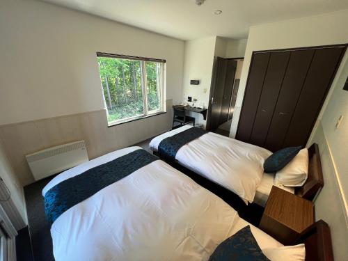 a bedroom with two beds and a window at Chalet Fuyuri in Furano
