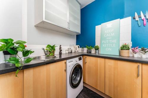 uma cozinha com um lavatório e uma máquina de lavar roupa em Traditional 1-Bed Flat in Southside (Hampden/Shawlands) em Glasgow