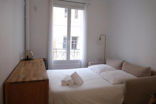 - une chambre avec un lit blanc et 2 serviettes dans l'établissement Très joli T2 cosy et calme, Butte aux Cailles, à Paris