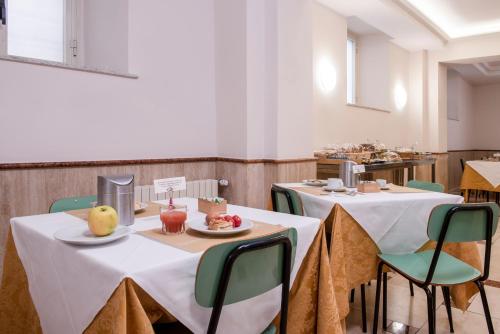 Casa San Giuseppe في روما: غرفة بطاولتين وكراسي عليها طعام