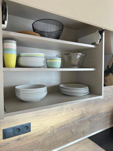 a cabinet with plates and bowls in it at Apartmány nad Anenským potokem - Říčky in Říčky