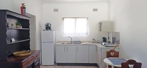 La cuisine est équipée de placards blancs et d'un réfrigérateur blanc. dans l'établissement Pumula on 5th, à Pumula