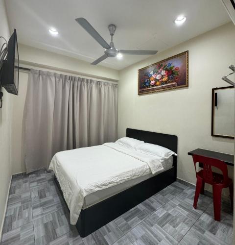 a bedroom with a bed and a table and a ceiling fan at 西子楼 CZI Budget Hotel Sungai Siput in Sungai Siput