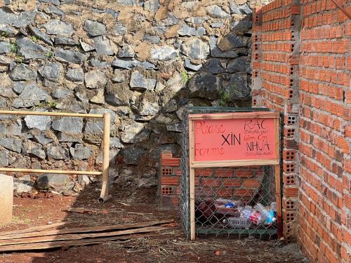 a sign with graffiti on it next to a brick wall at Homestay Caskameo Đà Lạt in Tarklette