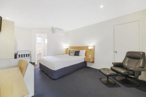 una habitación de hotel con una cama y una silla en Hamilton Townhouse Motel, en Hamilton