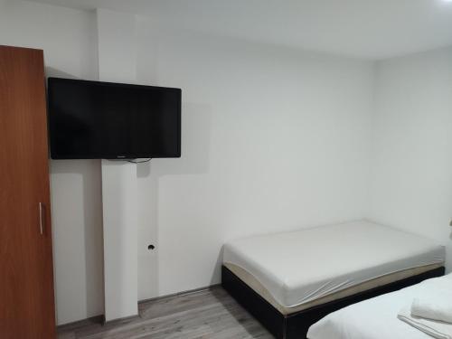 Apartmani Hub في نيشْ: غرفة نوم مع سرير وتلفزيون بشاشة مسطحة على جدار