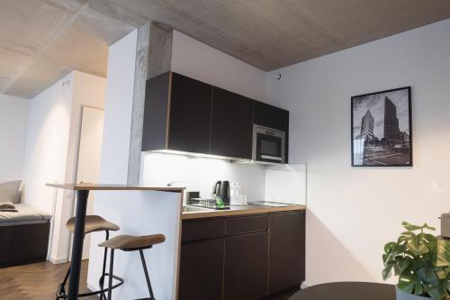 una cocina con armarios negros, mesa y taburete en NEOApartments, en Berlín