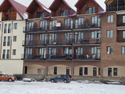 a large apartment building with cars parked in front of it at TWO-ROOM APARTMENTS in BAKURIANI in Bakuriani