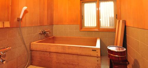 a wooden tub in a bathroom with a window at Ryokan Imai in Shibata