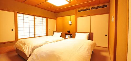 a bedroom with two beds and a window at Ryokan Imai in Shibata