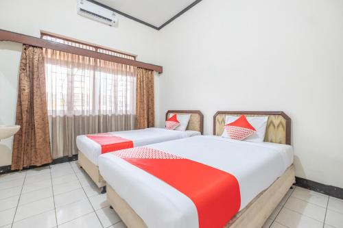 two beds in a room with a window at SUPER OYO 2703 Hotel Transit 1 in Makassar