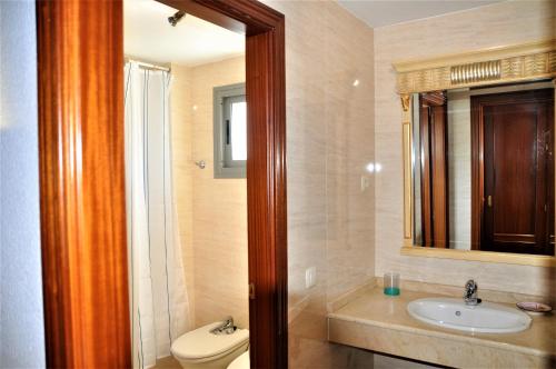a bathroom with a toilet and a sink and a mirror at Fuengirola - Luxury 3 bedrooms apartment in Fuengirola