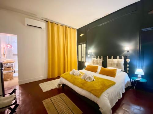 a bedroom with a large bed with yellow curtains at La parenthèse gourmande avec clim et parking in Montauban