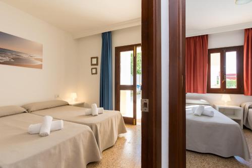 a bedroom with two beds and a couch at Apartamentos Casa del Sol in Cala Blanca