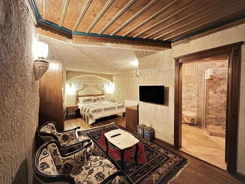 a living room with a bed and a couch and a television at Stone House Cave Hotel in Goreme