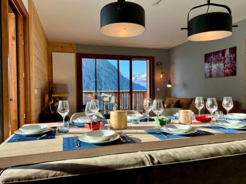 - une table à manger avec des verres et des assiettes dans l'établissement Les Loges Blanches - Apt C001 - BO Immobilier - Châtel, à Châtel